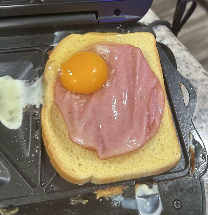 Raw egg and ham on toast in a toaster oven, a bananasausage food crime.
