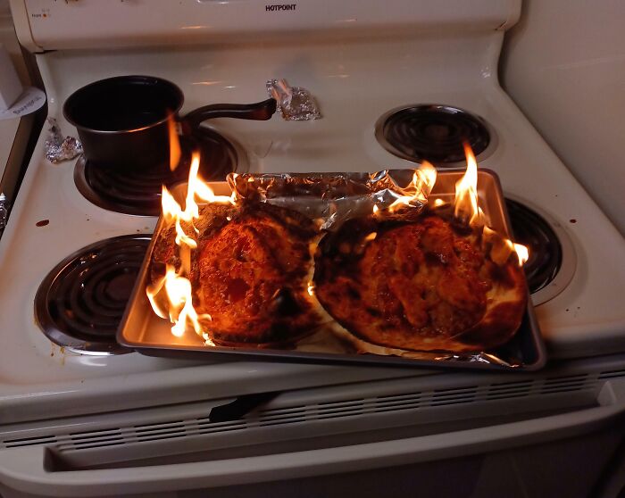 Bananasausage burning on a baking sheet on a stovetop, a food crime scene with active flames.
