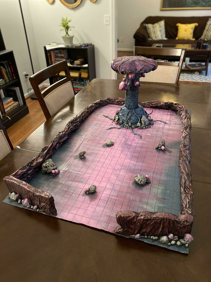 A handcrafted fantasy terrain board with a large purple mushroom, showcasing creative ways trash became artistic.