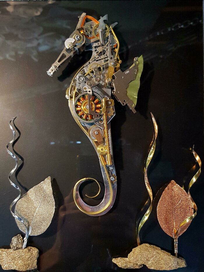 A seahorse sculpture made from recycled computer parts and gears on a dark background. Creative people transform trash into art.