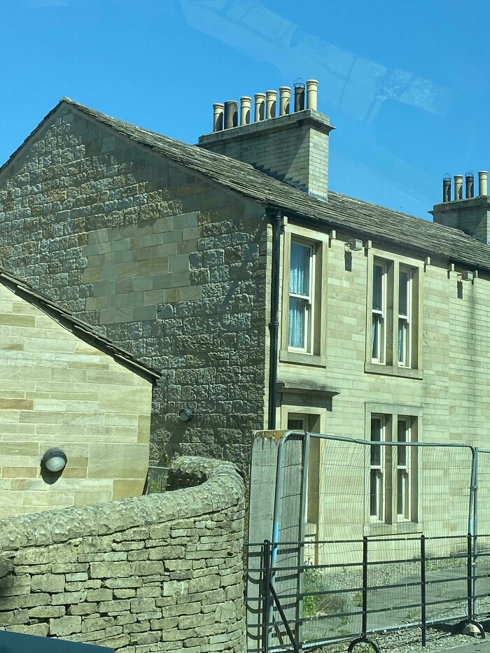 Stone home with multiple chimneys against a blue sky, showcasing unique architecture for home improvement insights.