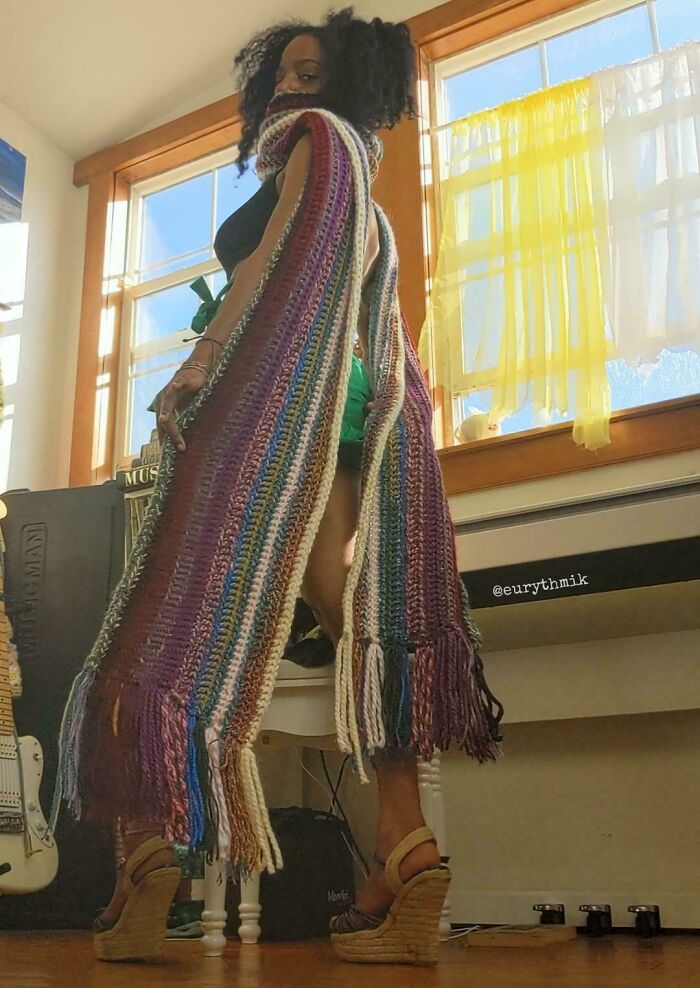 A woman wearing a vibrant, artistic, multicolored crochet scarf that showcases creative people's designs.