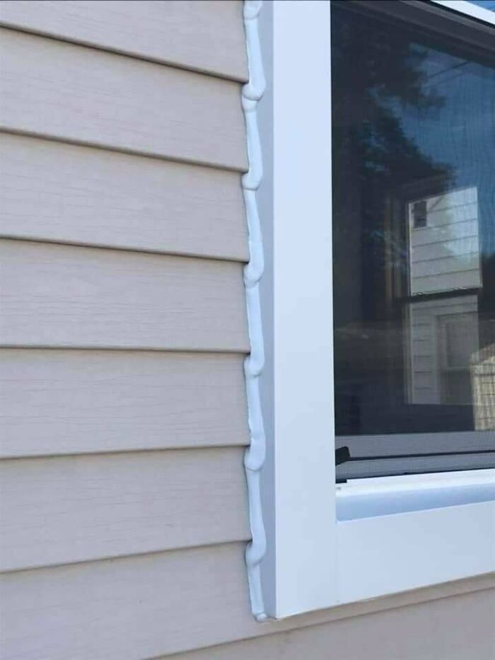 Poorly applied caulk along house siding and a window frame, a common home improvement fail.