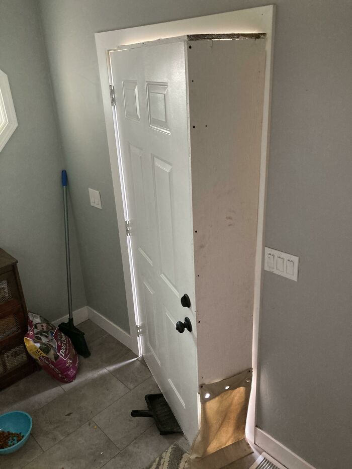 A white interior door hung improperly, showing a significant gap at the top and side. A home improvement fail.