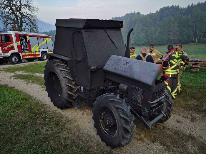 A black tractor on a dirt path with firefighters and an emergency vehicle, showcasing scenes that won't make sense to city kids.