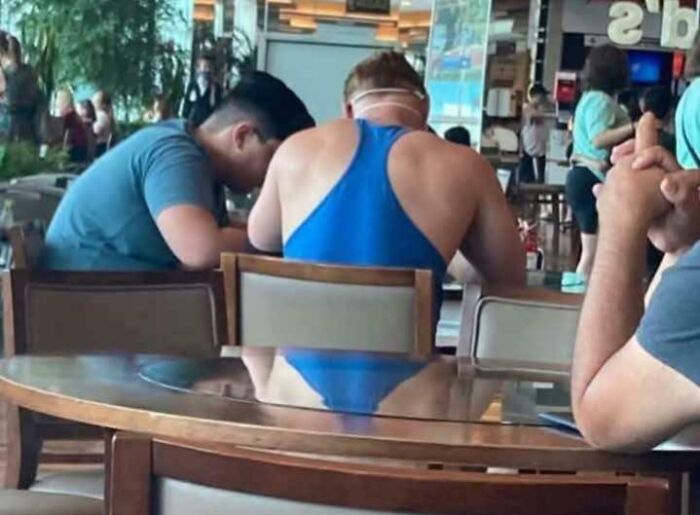 Man wearing blue swimsuit seated at a table in a restaurant, creating a misleading and confusing photo effect.