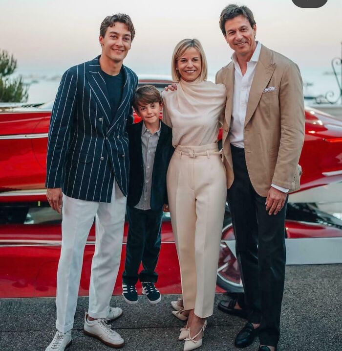 Group of four people posing in front of a red car, creating a misleading and confusing photo that seems like a glitch in real life