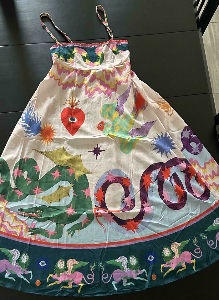 Vibrant white dress with whimsical dragon, heart, and mythical creature illustrations, a fabulous thrift store jackpot.