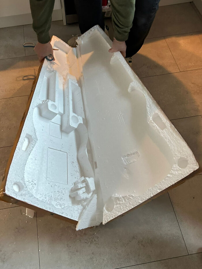 Person opening styrofoam packaging meant for a guitar, but it's empty. A lesson learnt from ordering from Temu or AliExpress.