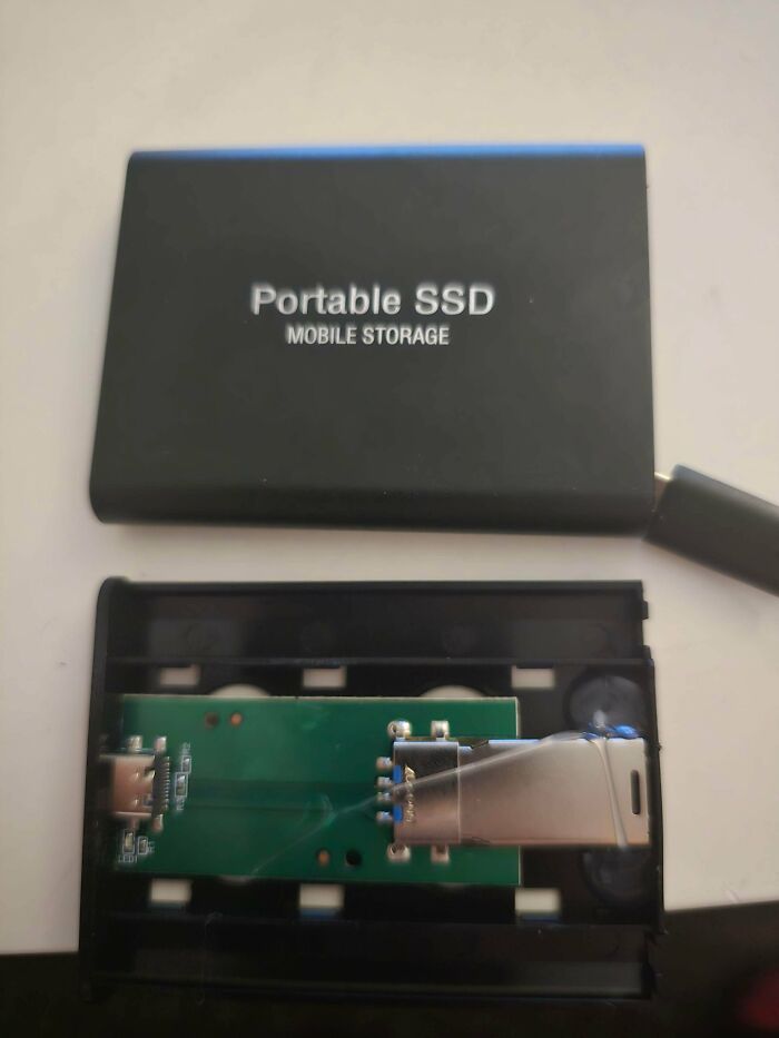Fake Portable SSD from Temu or AliExpress, opened to reveal a simple USB drive connected inside the misleading case.