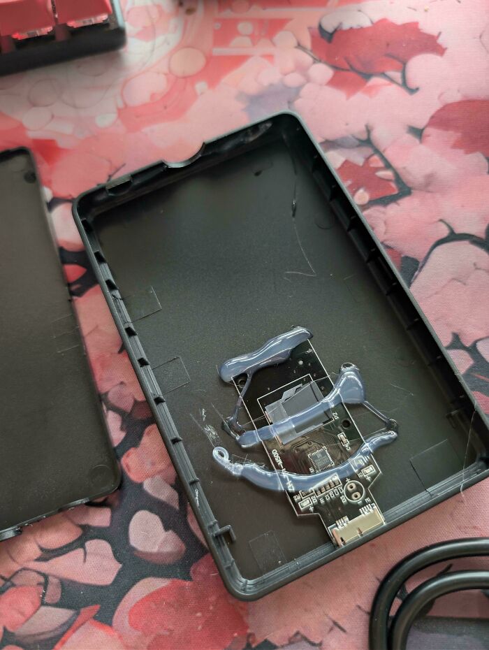 Shoddy hard drive enclosure from Temu Or AliExpress with a circuit board haphazardly glued inside.