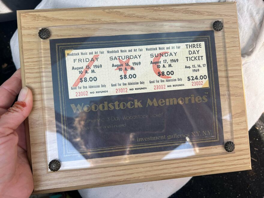 A hand holds a framed Woodstock ticket, one of the suspiciously good things found in Goodwill bins.