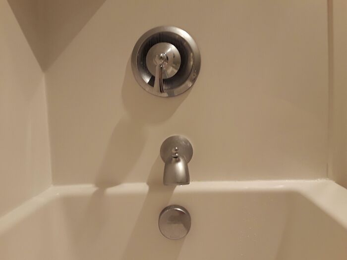 A white bathtub with chrome fixtures, including a faucet and shower handle. A potential home improvement fail.