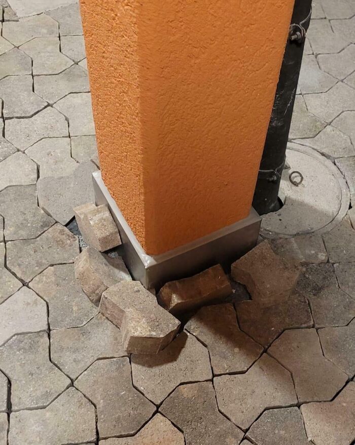 A home improvement fail: loose concrete pavers around the base of an orange stucco pillar, near a downspout.