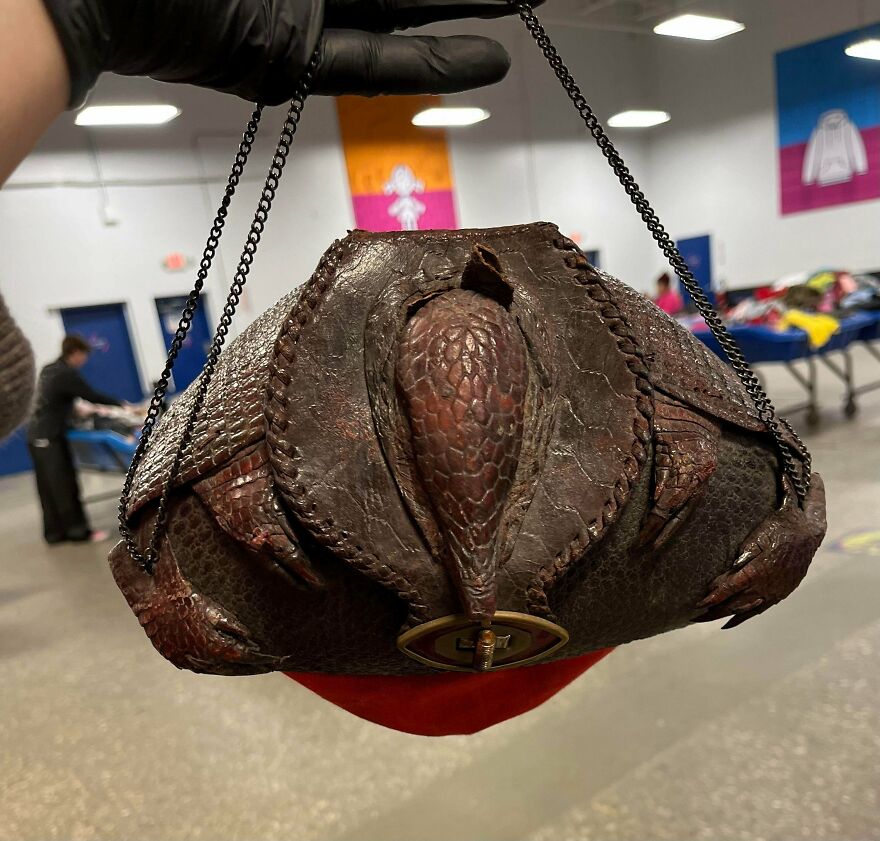 A person in black gloves holding a unique, dark, scale-textured handbag with a red lining. A Goodwill Bins find.