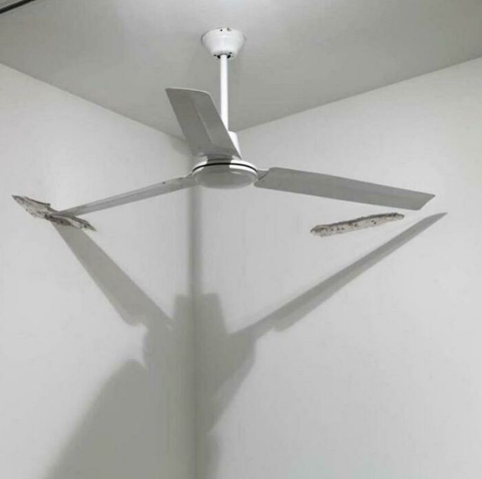 A broken white ceiling fan, with two blades damaged and concrete visible. A home improvement fail.