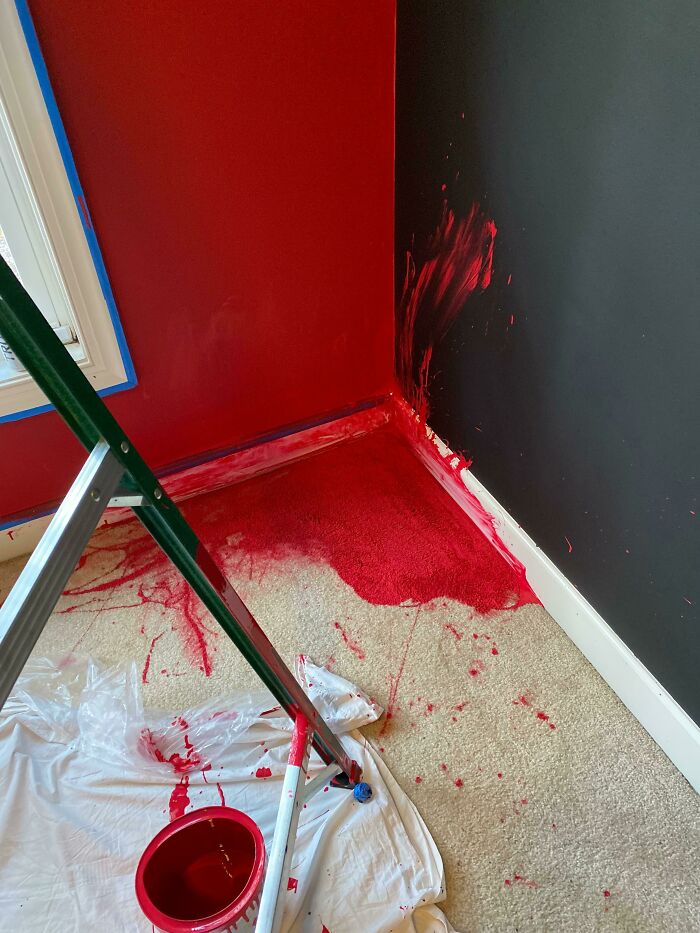 A massive home improvement fail: vibrant red paint splattered across walls, trim, and soaked into a light carpet.
