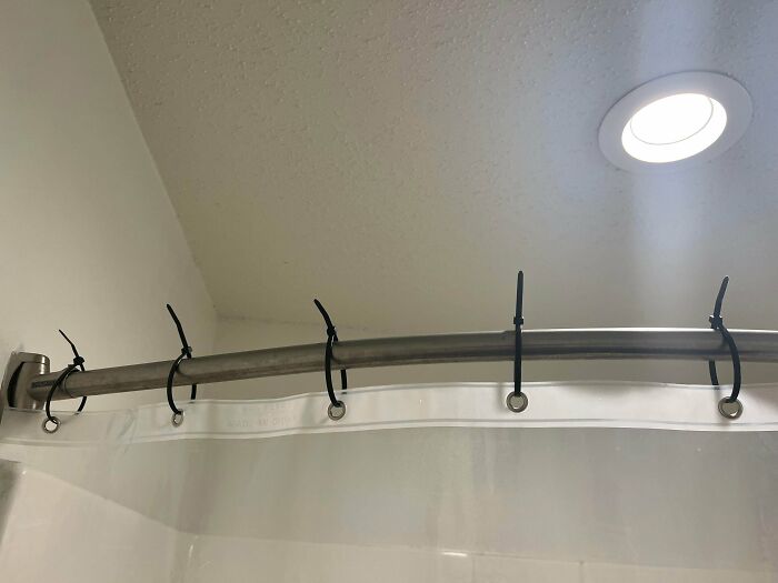 A shower curtain attached to a rod with zip ties, a home improvement fail.