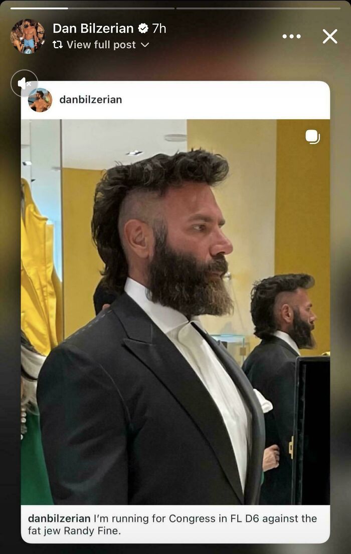 Dan Bilzerian in a suit, sporting a striking and unfortunate haircut with a prominent beard.