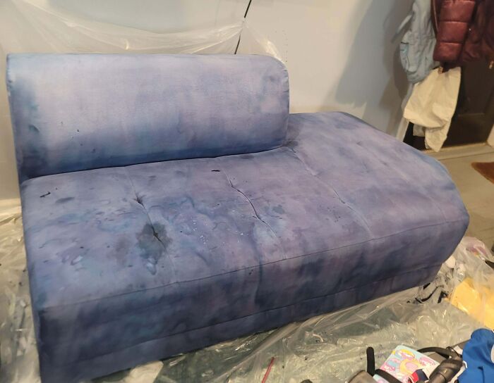 A blue sofa covered in dark stains, a home improvement fail, showing disastrous results.