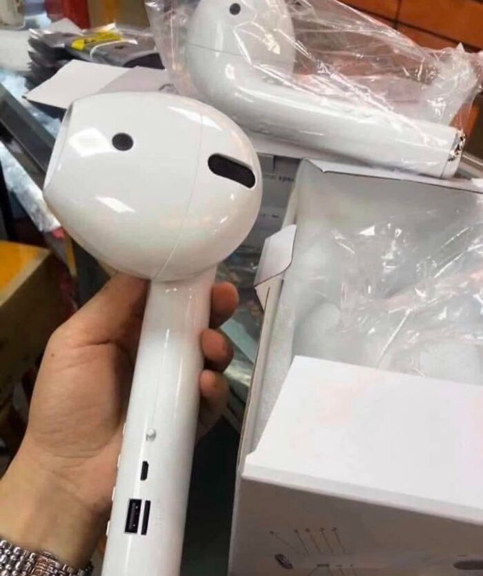 Lesson Learnt: Hand holds a giant fake AirPod speaker from a Temu or AliExpress order. Another in plastic wrap.