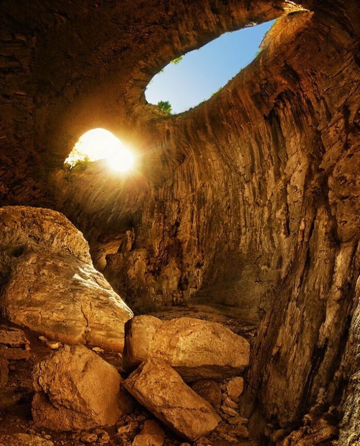 Breathtaking travel photo of a vast cave with natural light shafts revealing the sky above, showcasing Earth's beauty.