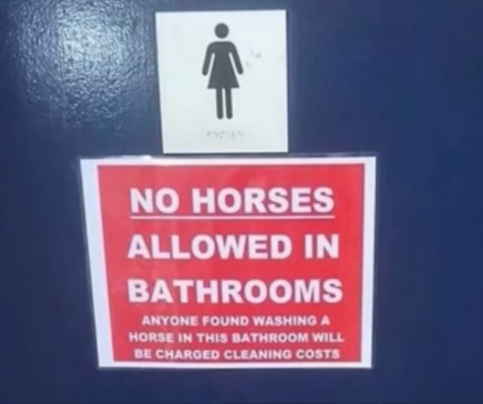 A female restroom sign above a red sign stating No Horses Allowed in Bathrooms, an oddly specific rule.