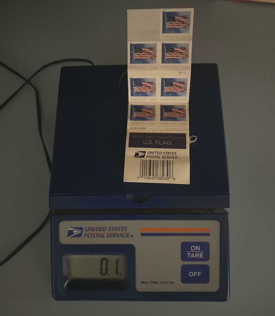 A sheet of U.S. flag stamps on a postal scale, showing the weight. A Goodwill bins find.