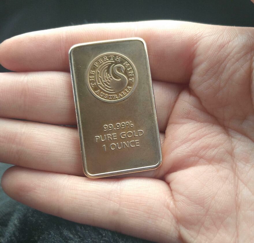 A hand holding a Gold Bar from The Perth Mint, marked 99.99% Pure Gold, 1 Ounce. Found in Goodwill bins.