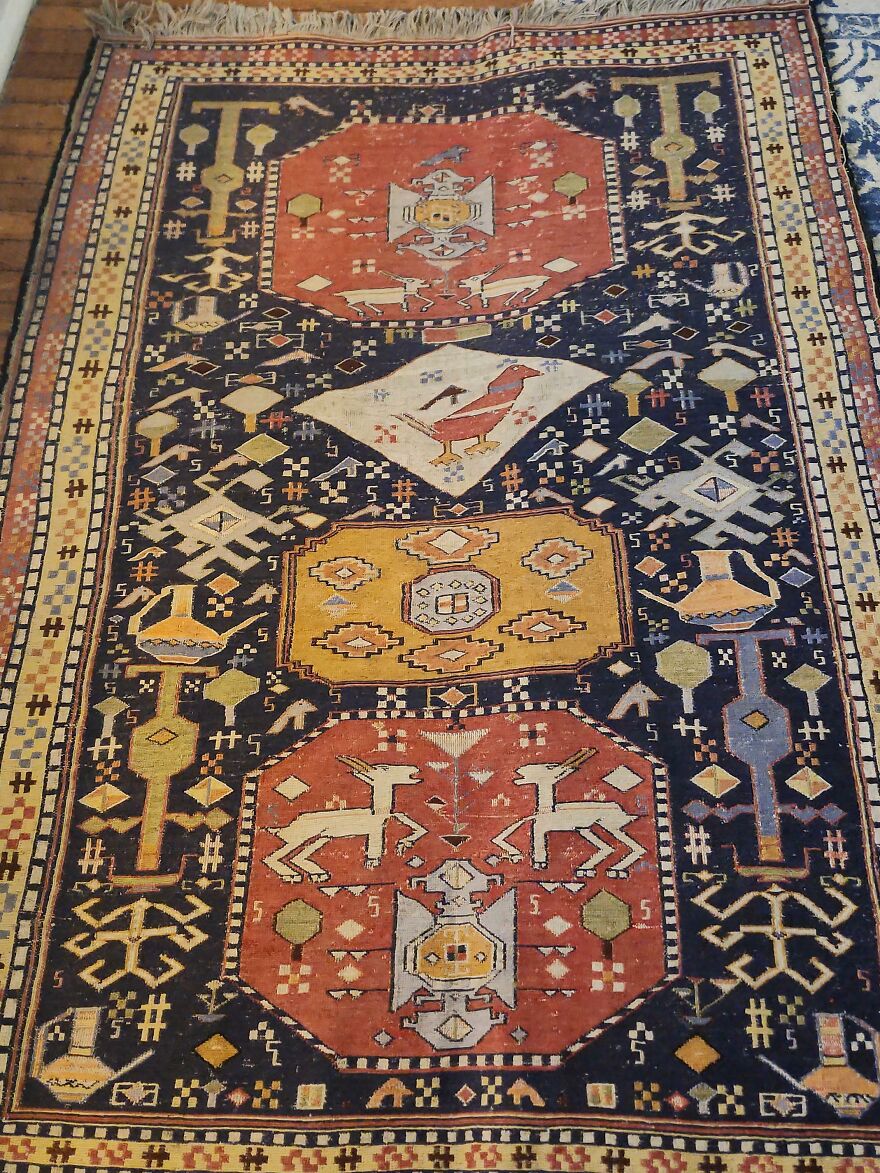 A colorful, patterned rug, a suspicious good thing found in Goodwill bins, featuring abstract animals, birds, and geometric shapes.
