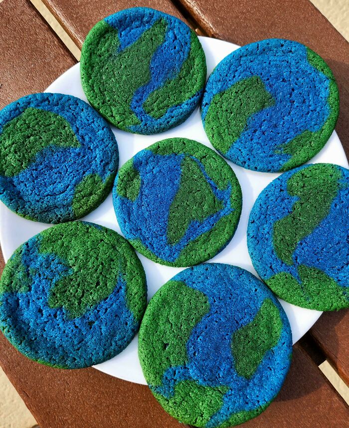Earth-themed cookies with blue and green icing on a white plate