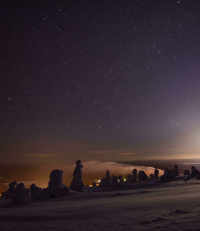 Unbelievable photos of a snowy landscape under a starry night sky, with distant lights, like glimpses into another universe.