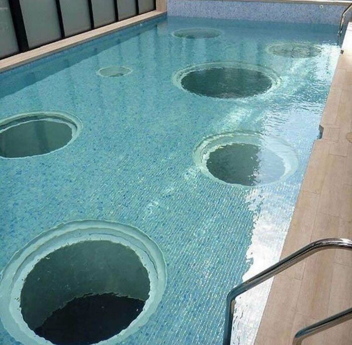 An uncomfortable water pic of a swimming pool with large, unsettling circular holes in the bottom, making one feel small.