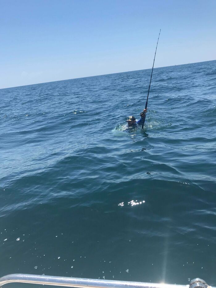 Man struggling in the vast ocean with a fishing rod, highlighting uncomfortable water pics that make you feel small.
