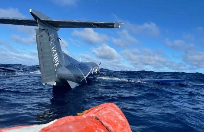 An uncomfortable water pic of a small plane partially submerged in the vast, deep blue ocean, making you feel small.