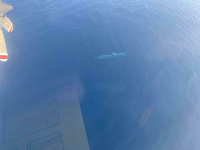 An aerial view shows a boat partially submerged in the vast, deep blue ocean, an uncomfortable water pic.