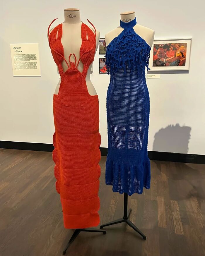 Two amazing crocheted dresses on mannequins: a red lobster-shaped gown and a blue fringed dress, awesome crochet art.