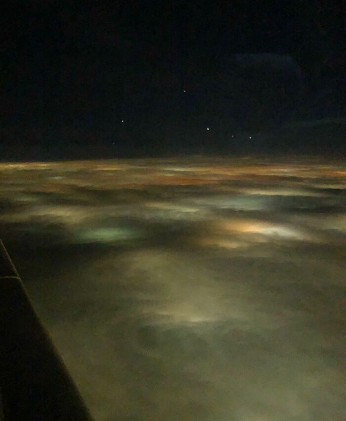 Unbelievable photos taken on Earth, a view from above clouds at night, city lights glowing through. Glimpses into another universe.