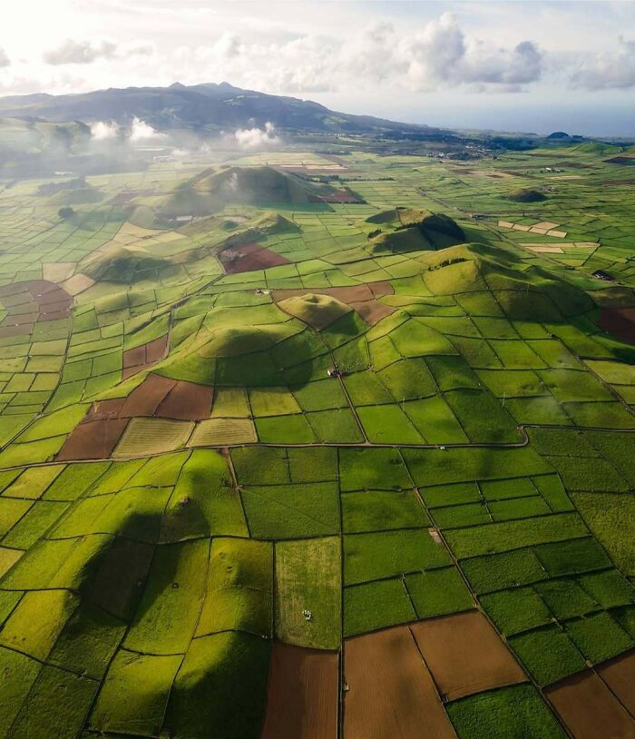 Unbelievable Photos Taken On Earth: An aerial view of lush green fields and rolling hills, a glimpse into another universe.
