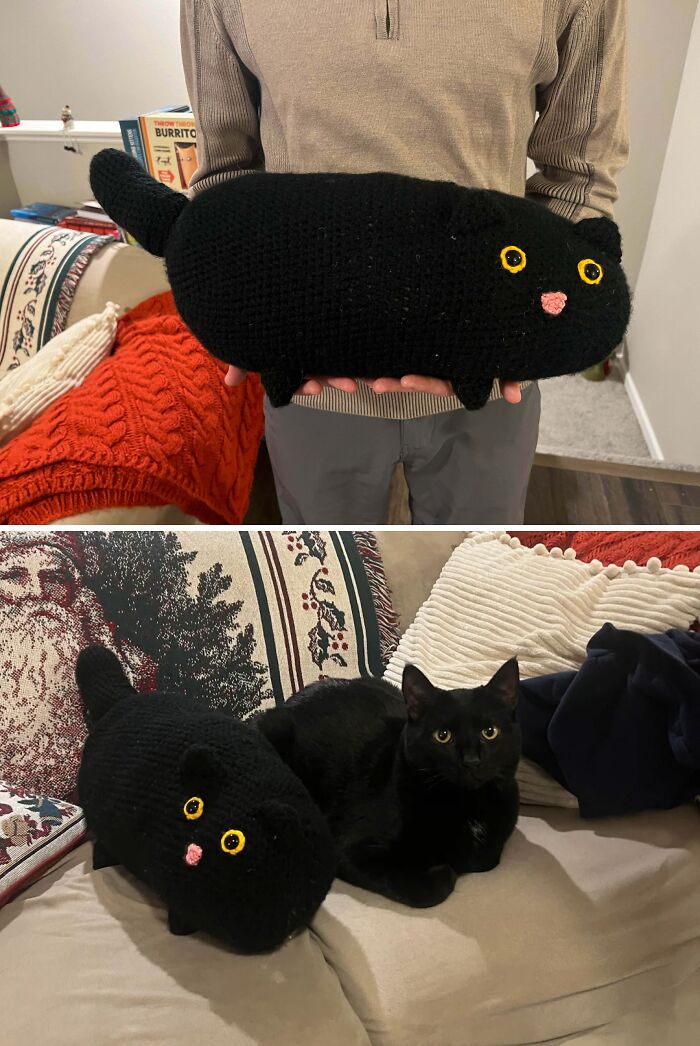 A person holds a black crocheted cat, while a real black cat rests beside a similar crocheted one on a couch. Awesome crocheted creations.