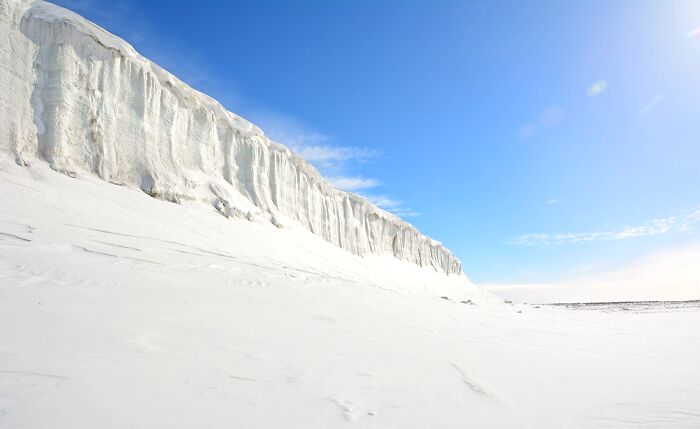 Unbelievable photos of a massive glacier wall and vast snowy expanse under a clear blue sky. Earth photos.
