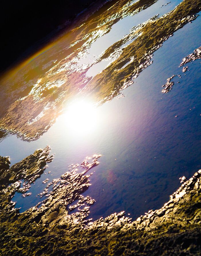 Unbelievable photos taken on Earth: aerial view of rocky terrain and water reflecting a bright sun, like another universe.