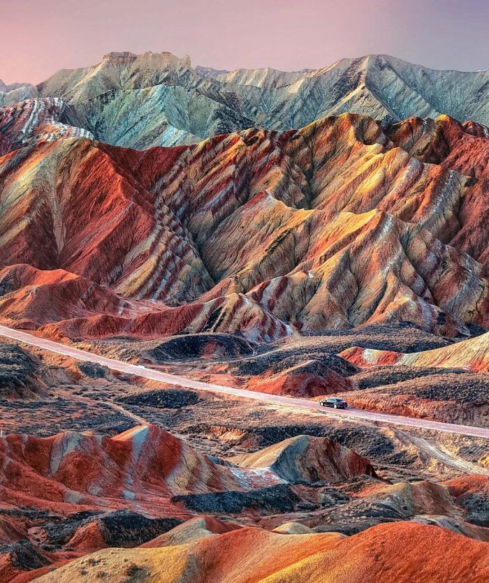 Unbelievable photos of Earth, showing a road winding through vibrant, rainbow-colored mountains, like another universe.