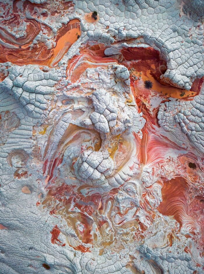 Unbelievable photos of Earth's patterns, resembling another universe with cracked white textures and red-orange swirls.