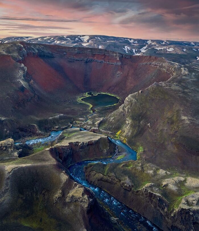 Unbelievable photos of Earth: An aerial view of a volcanic crater lake and winding rivers through a rugged landscape.