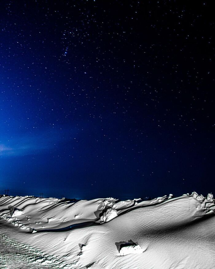 Unbelievable photos of a star-filled dark blue night sky over a snow-covered landscape, like another universe.