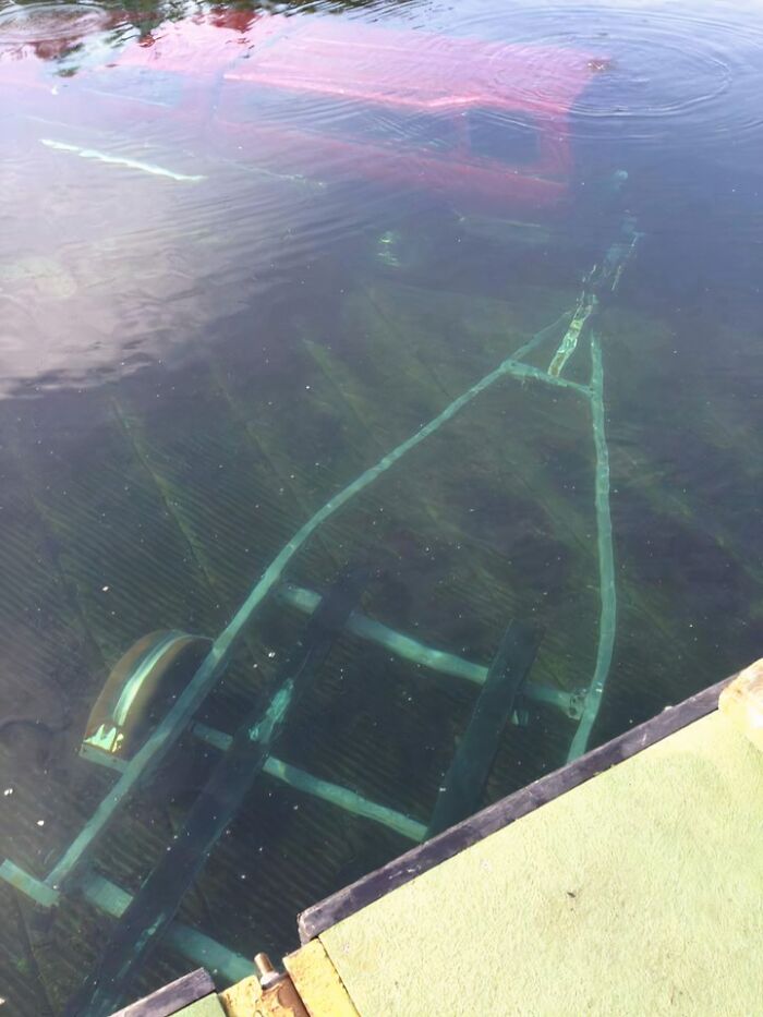 An uncomfortable water pic showing a partially submerged boat and trailer in murky water, near a dock.