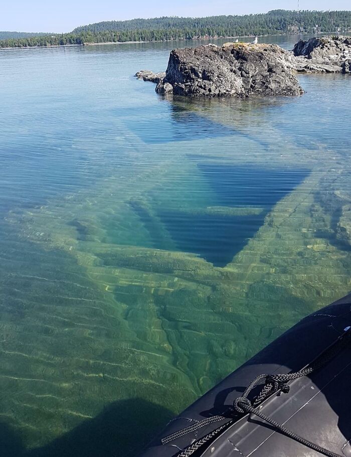 Clear, blue-green water revealing stepped underwater ledges near a rocky island. Uncomfortable water pics, making you feel small.