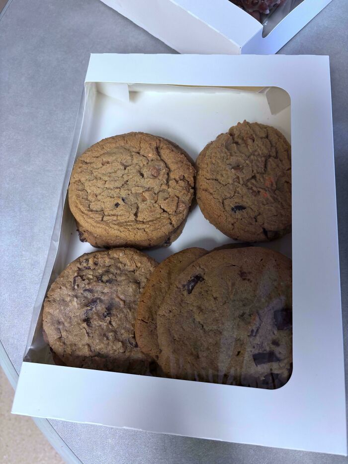 A white box filled with an assortment of Girl Dinner cookies, including chocolate chip and oatmeal raisin.