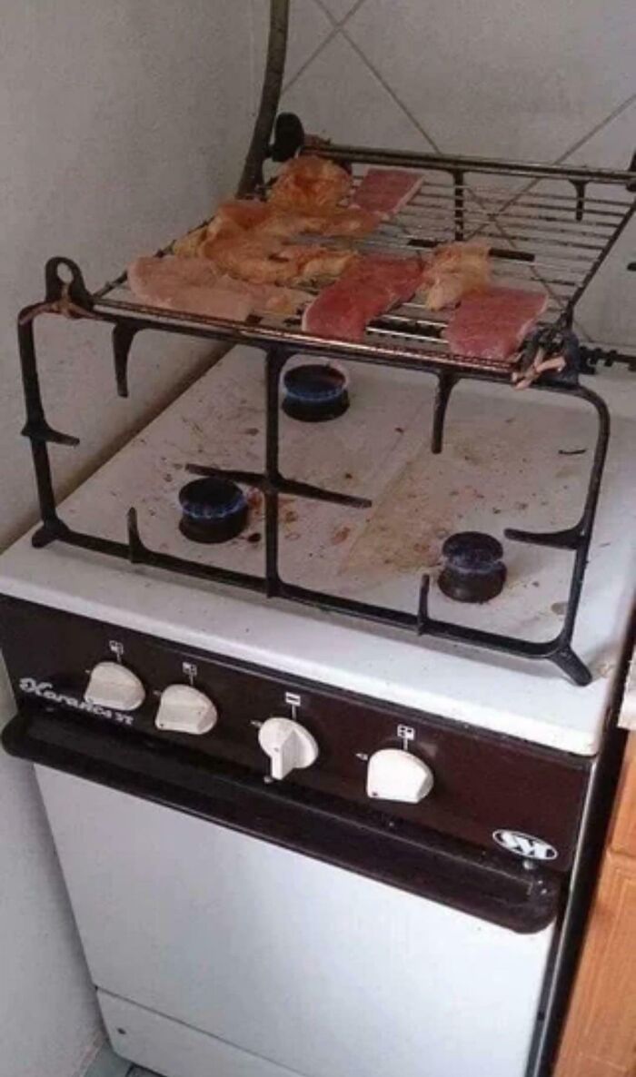 A DiWHY moment: a metal grilling rack with raw meat placed over a gas stove with active flames.